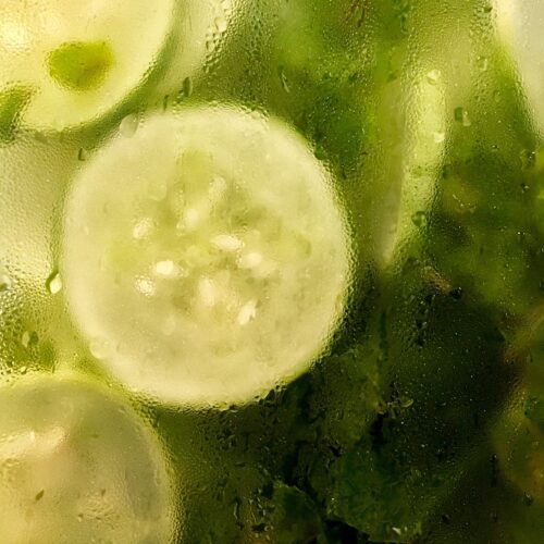 sliced pickled cucumbers in a glass jar covered with condensation