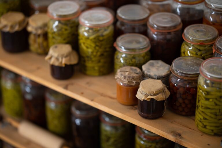 Many jars of preserves stored on pantry shelf