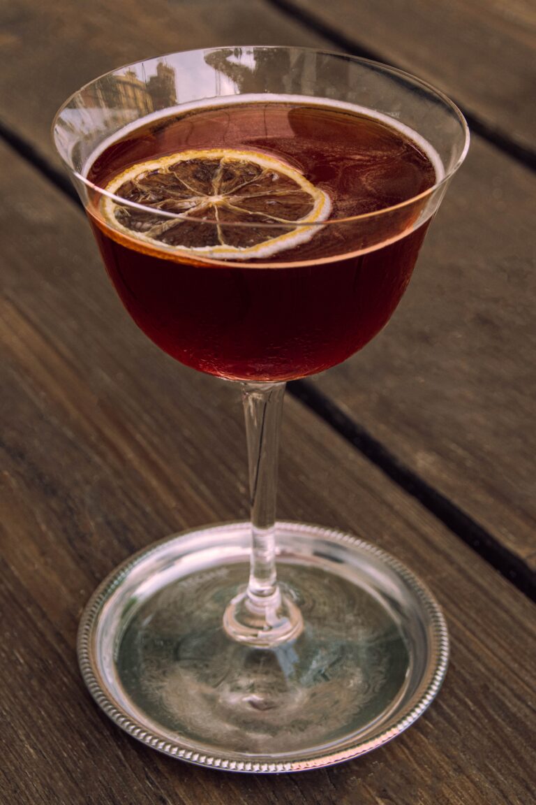 A wine glass of damson gin with a lemon slice garnish