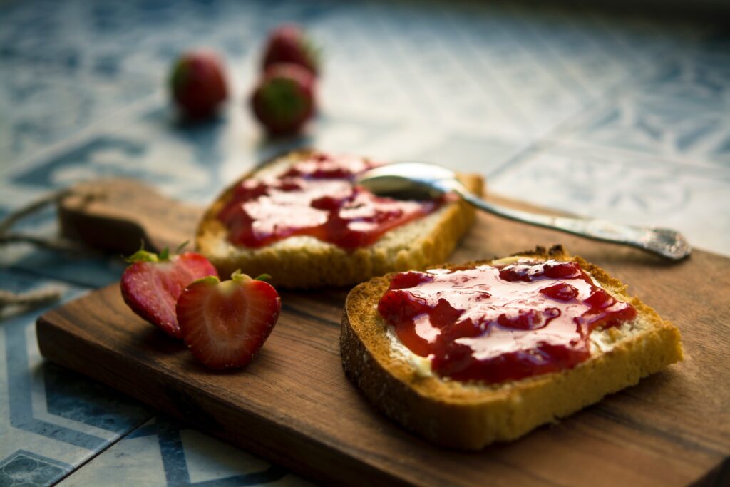 freezer strawberry jam on toast, with fresh strawberries on boards and in the background