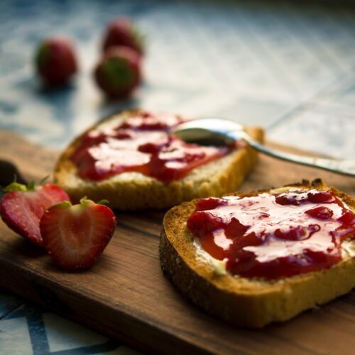 freezer strawberry jam on toast, with fresh strawberries on boards and in the background