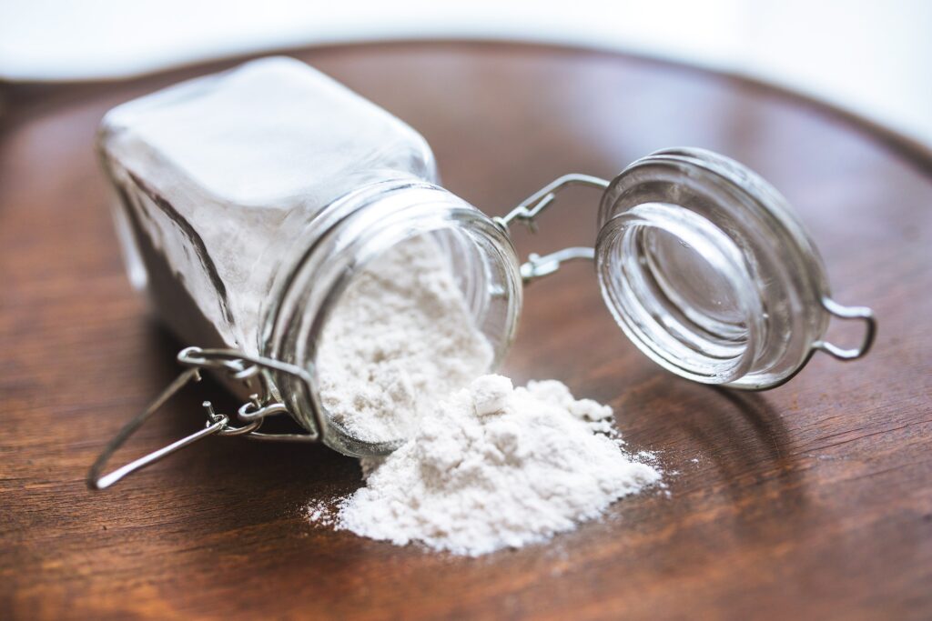 Jar of white cornflour spilling onto table