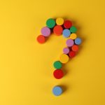 A question mark shape made up of multicoloured round cylinders on yellow background.