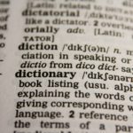 A close up image of a dictionary showing the definition of 'dictionary' an nearby words