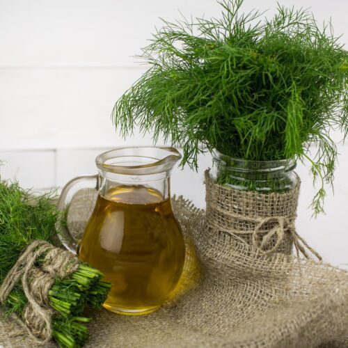 Dill in water next to olive oil on chopping board