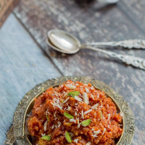 Carrot chutney in an ornate metal bowl with garnishes ready to eat on a table.