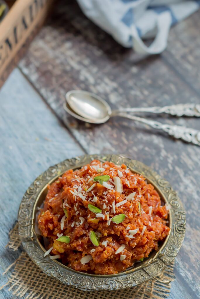 Carrot chutney in an ornate metal bowl with garnishes ready to eat on a table.