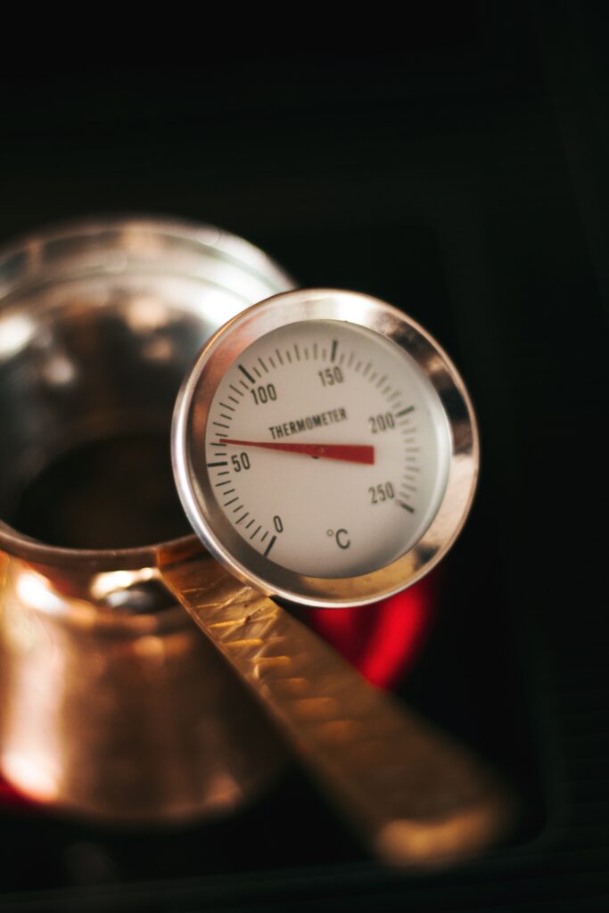 Thermometer with dial face standing in a small copper pot