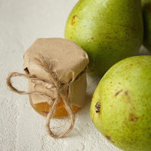 Close up photo of conference pears with a small jar of pear jam