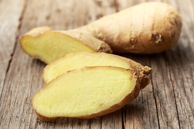 Ginger root with a couple of slcices, on wooden board