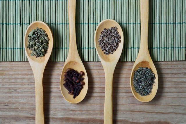 Dried spices on wooden spoons lined up.