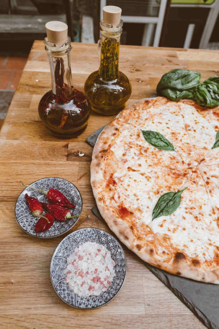 Pizza with a small bowl with chilli, and a bottle of chilli vinegar and one of herb oil.