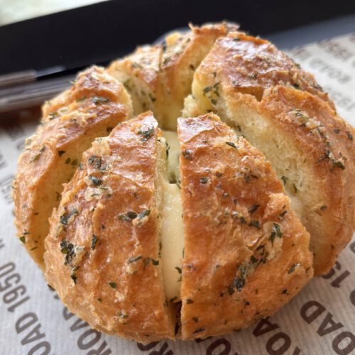 Round bread loaf cut into wedges and filled with rounds of lemon thyme compound butter