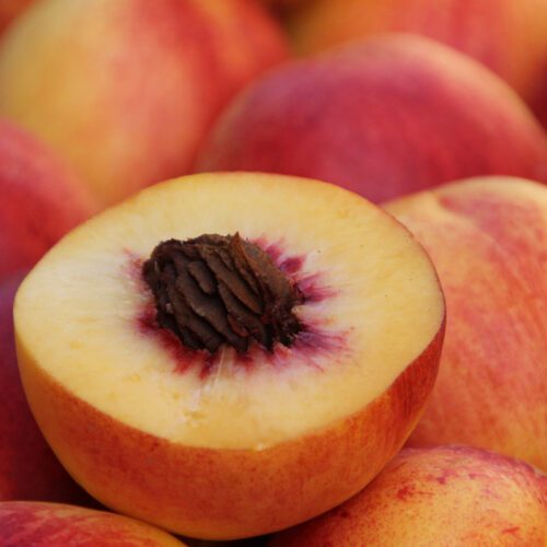 Peaches, with one cut in half showing the stone.