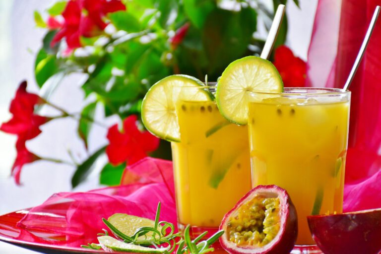 Two glasses of chilled passionfruit cordial drinks, with a cut passionfruit in the foreground.