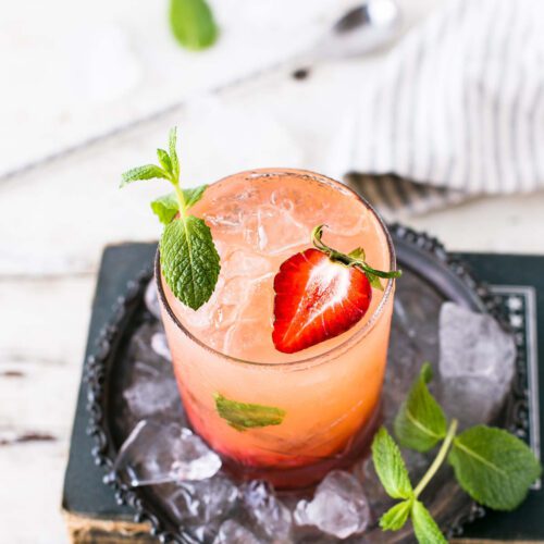 Strawberry mint shrub drink with a sliced strawberry and mint leaf garnish.