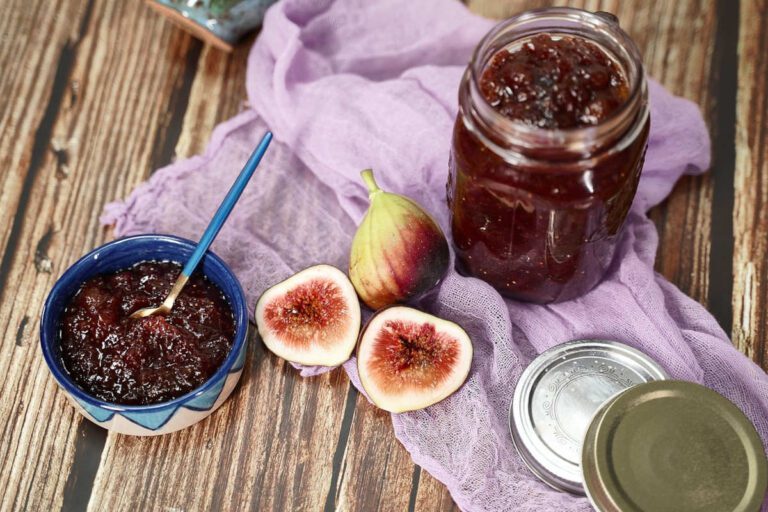 A jar and a bowl of fig and ginger jam, with a whole and cut fig alongside.