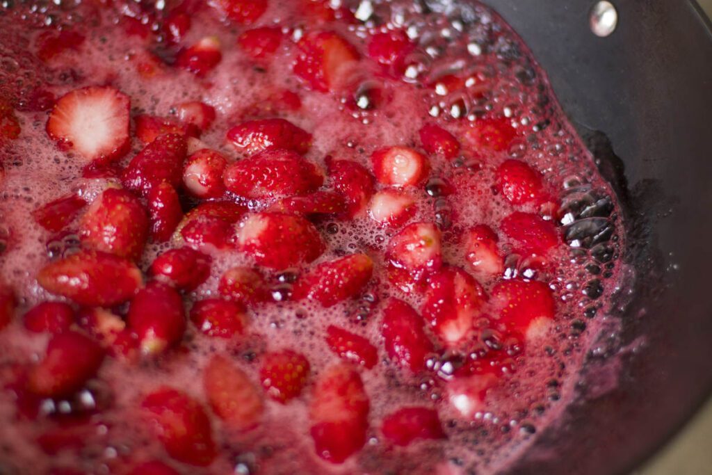 Close-up image of strawberries boiling in syrup.