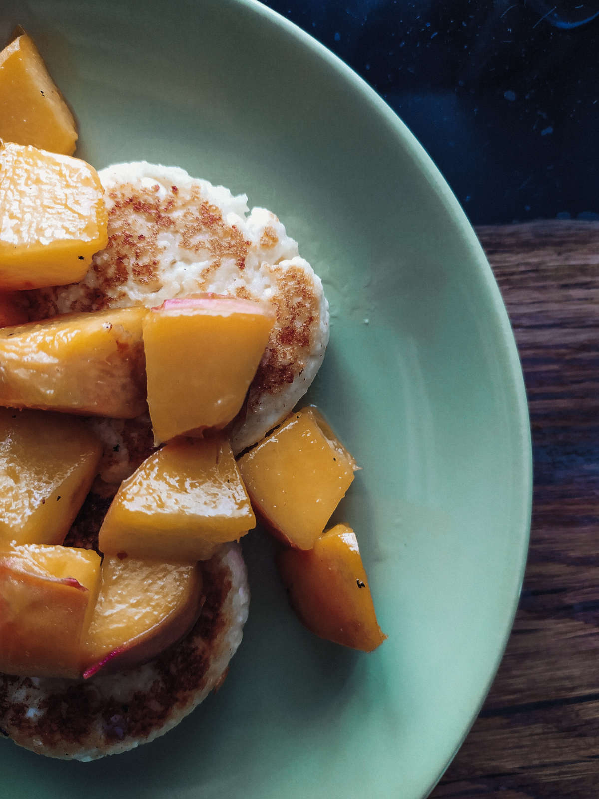 Chopped up pieces of peach on two pasties on a green plate