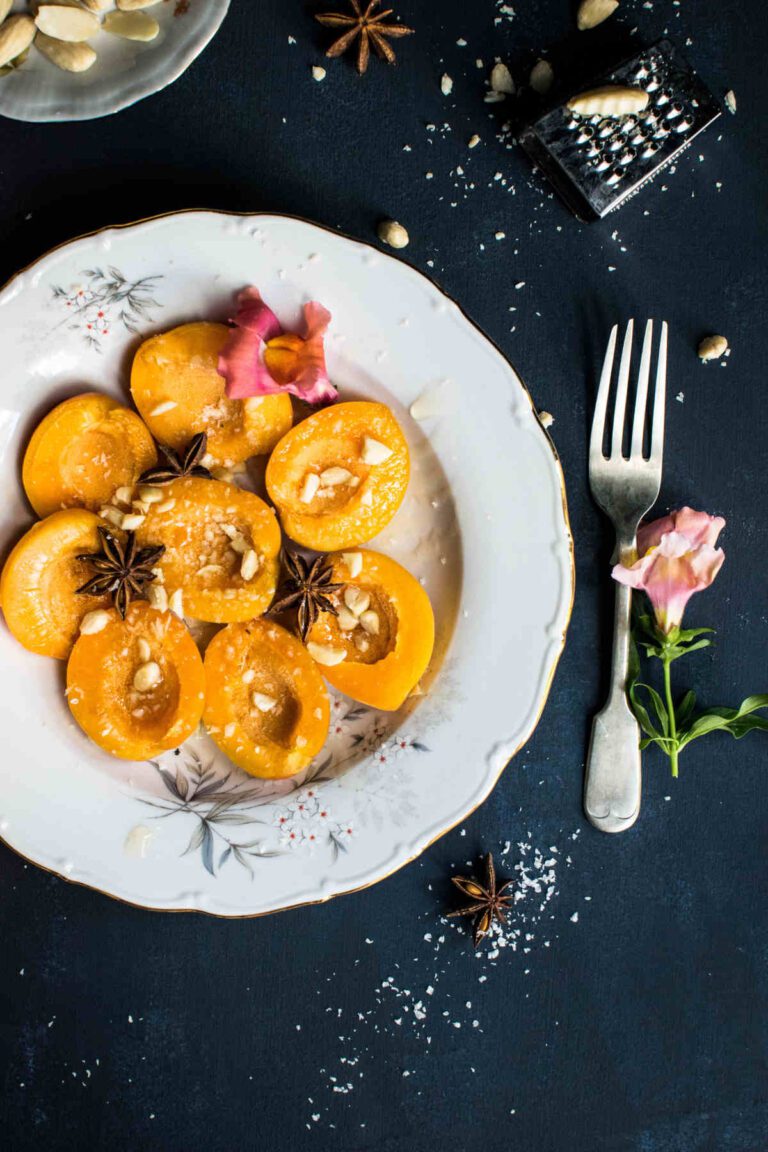 Peach halves on a white floral plate, garnished with star anise, buts and a flower.